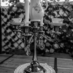 Candelabro vintage con tetera de porcelana blanca con flores verdes, tazas a juego, cristales colgantes y tapete de crochet blanco perfecto para un estilo unico y acogedor