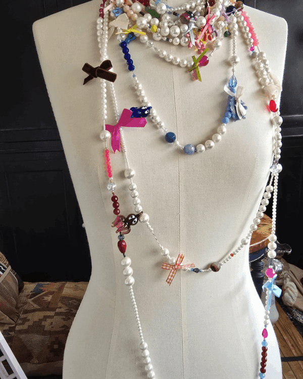 Collar Apfel artesanal de perlas majoricas con cristales de colores, ágathas y lazos decorativos, presentado sobre busto de costura